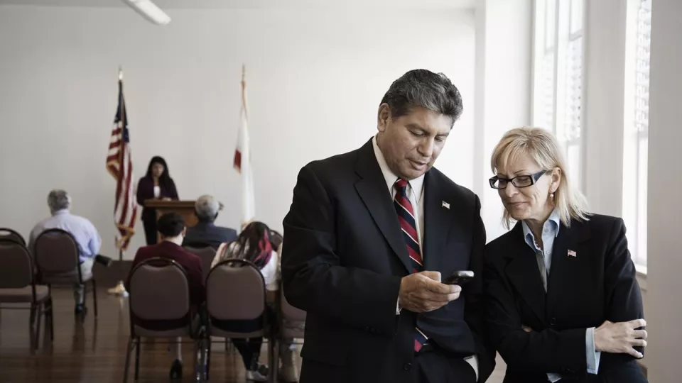 Two people in a courtroom check a phone
