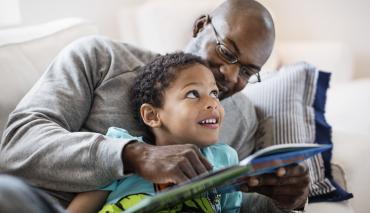 A father and son enjoying a book they received from a program they joined via short code enrollment
