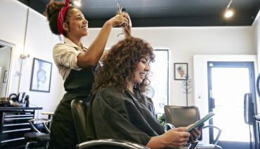 A woman getting her hair done at an appointment she made using the salon's short code scheduler