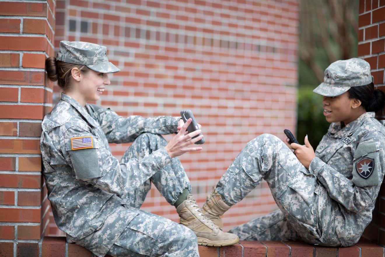 Two soldiers chat about an upcoming event alert sent via short code to the mobile phones