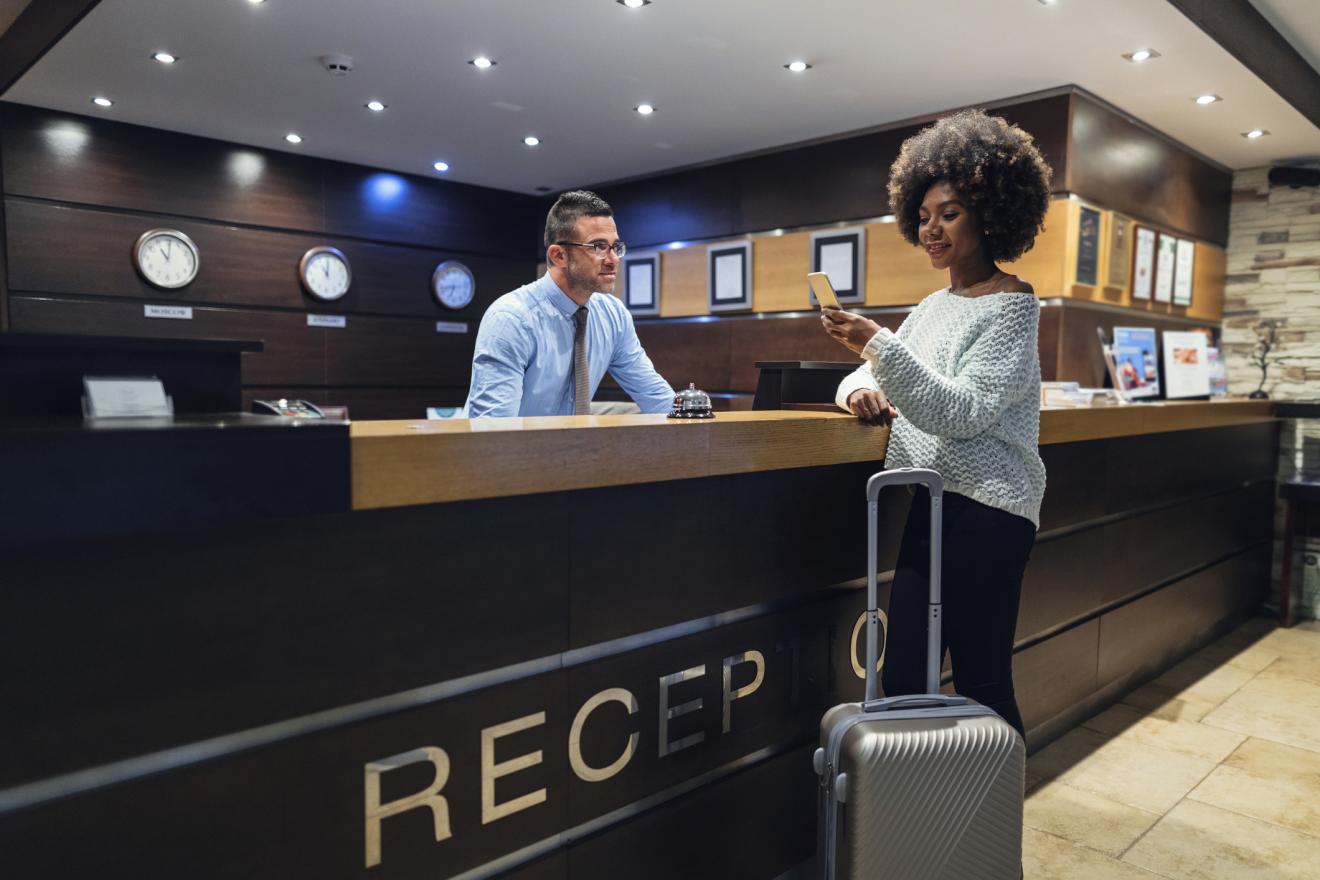 Woman receives an update on her mobile phone while checking into a hotel