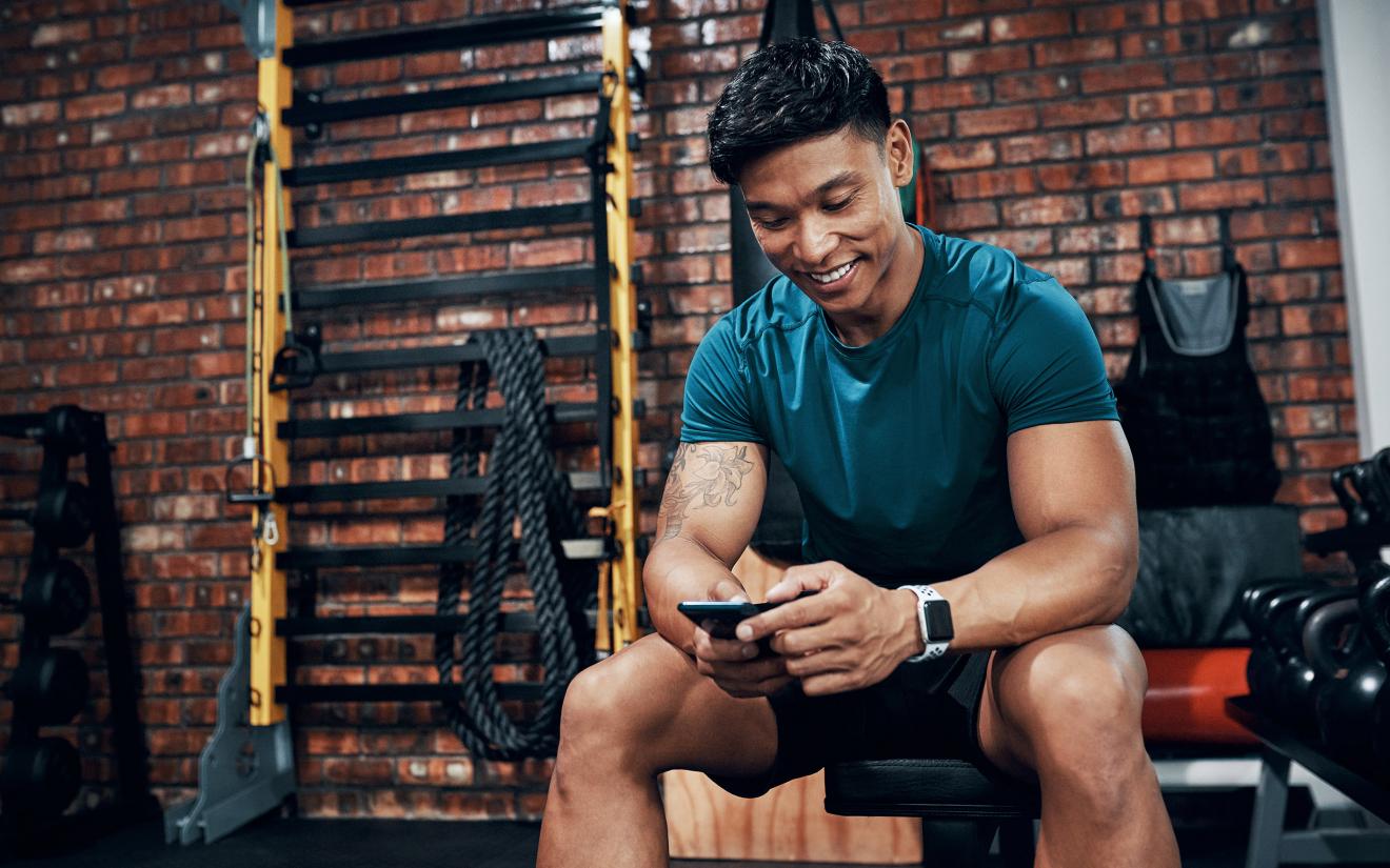 young-man-redeeming-benefits-on-his-mobiile-phone-at-the-gym-smart-codes-program