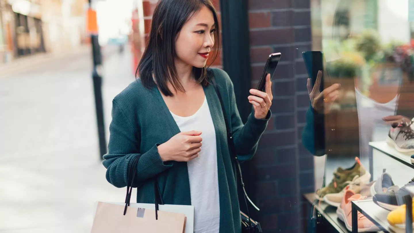 A distracted woman checks her phone while shopping
