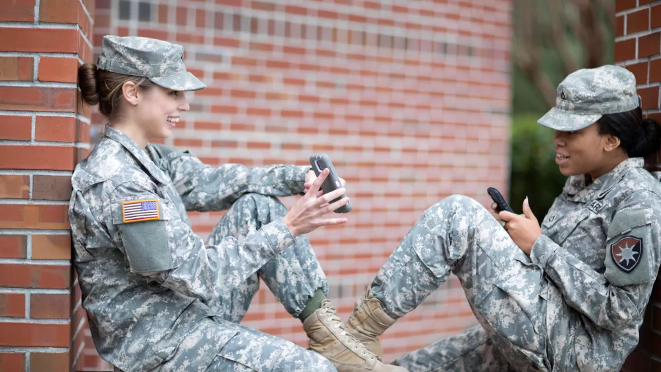 Two soldiers chat about an upcoming event alert sent via short code to the mobile phones